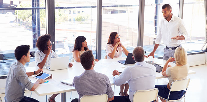 Directors & Officers Liability Insurance: A team of people sitting at a table, looking up to their team leader.