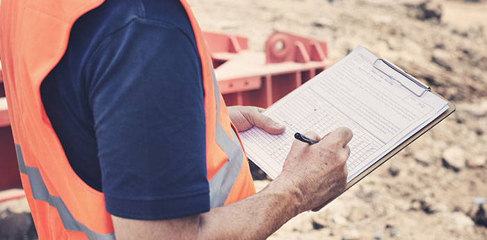 Products Liability Insurance: A man in a Hi Vis Jacket filling in a document on a clipboard.