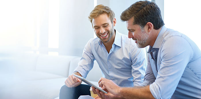 Professional Indemnity Insurance: Two men smiling and looking at a tablet together. 