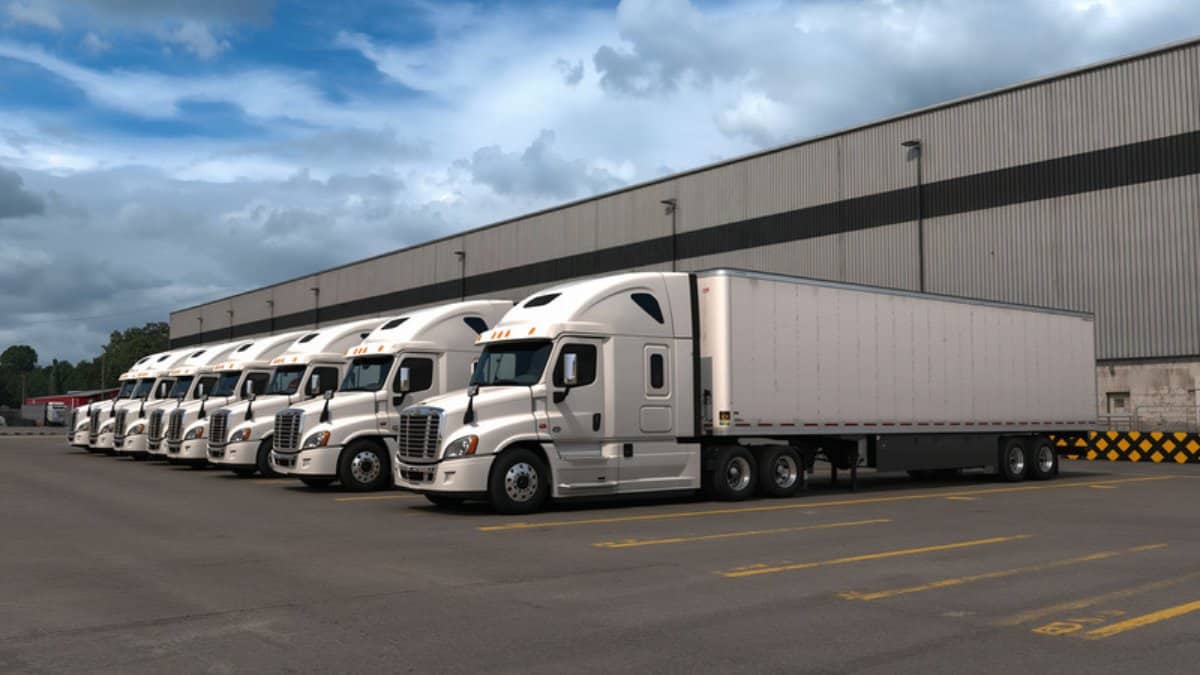 White commercial trucks parked at a logistics depot