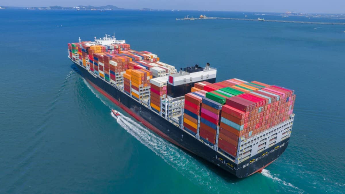 Red container ship carrying cargo across open sea